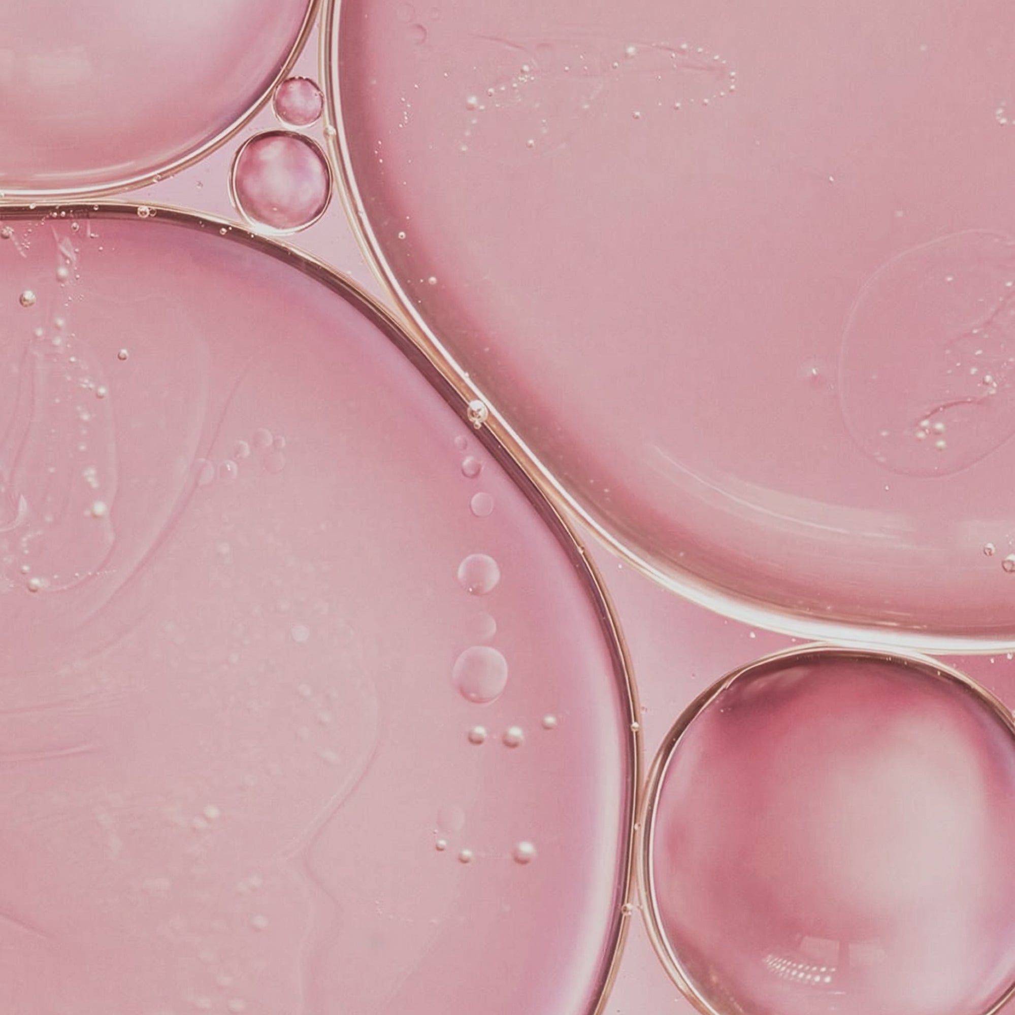 Close-up of pink liquid with bubbles and a gold ring